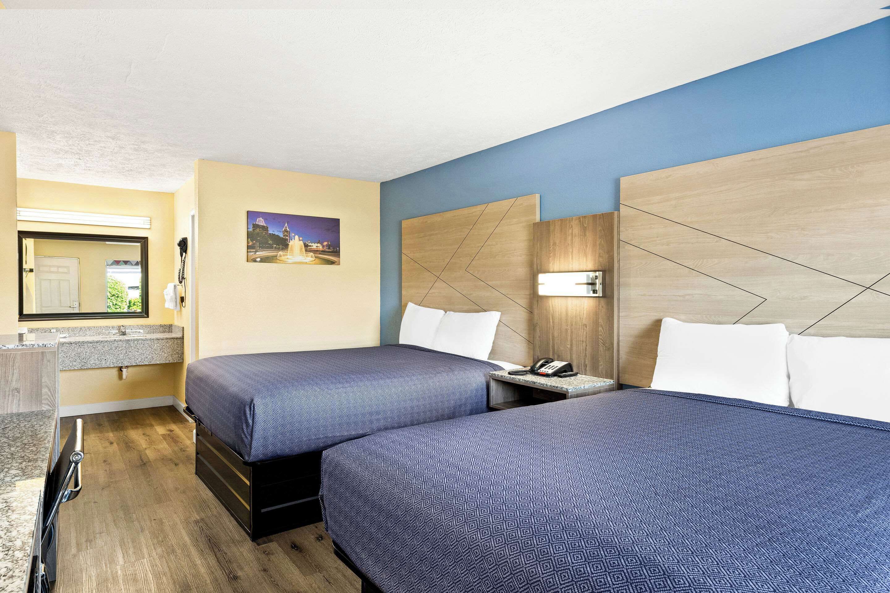 Habitación de hotel con dos camas, baño y un pequeño rincón de descanso.
