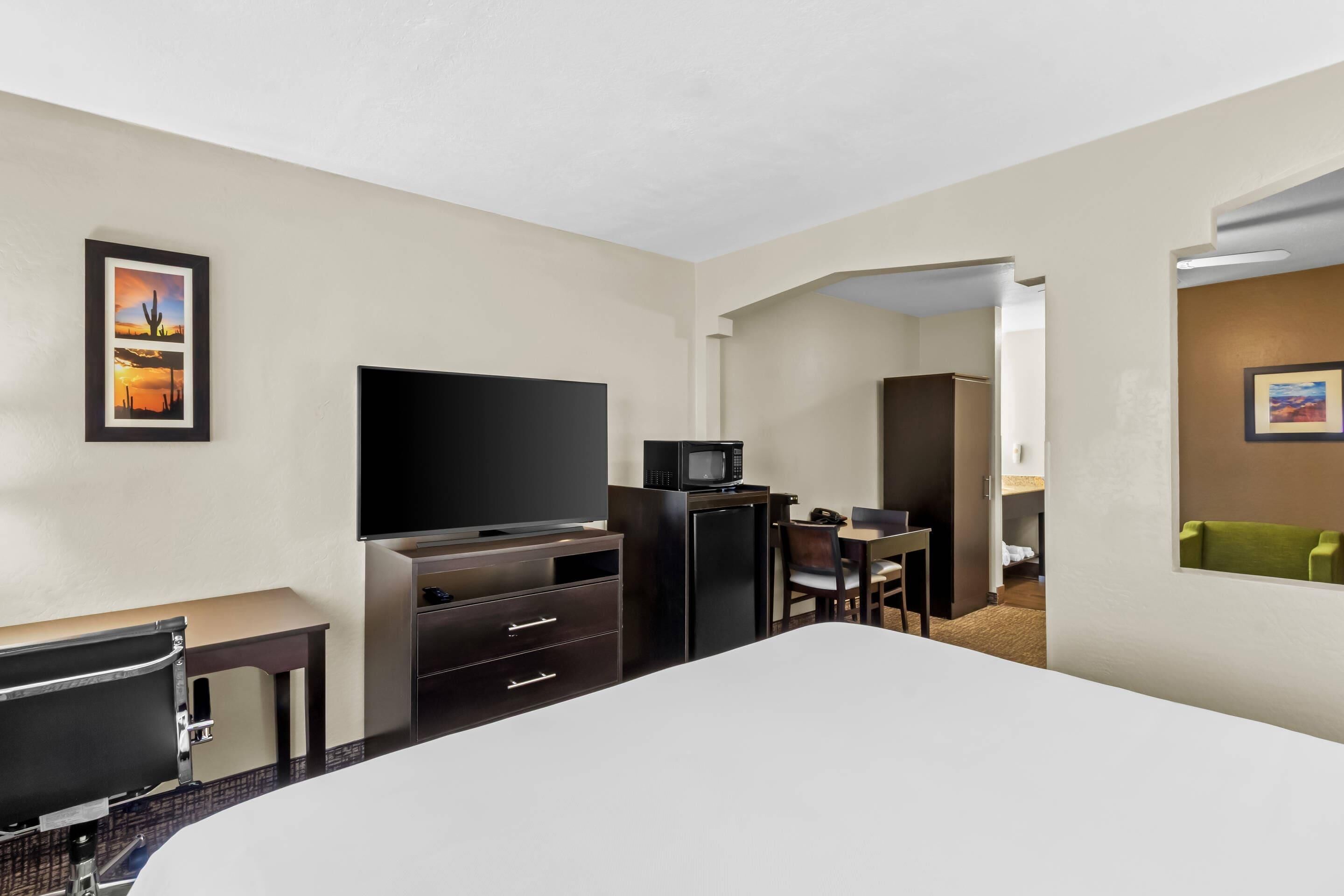 Ein Hotelzimmer mit Bett, Schreibtisch, Fernseher, Mikrowelle und Stuhl.
