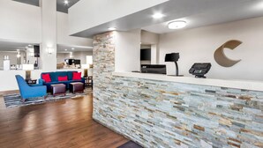 A modern reception area with a stone wall, a blue sofa, and a wooden floor.