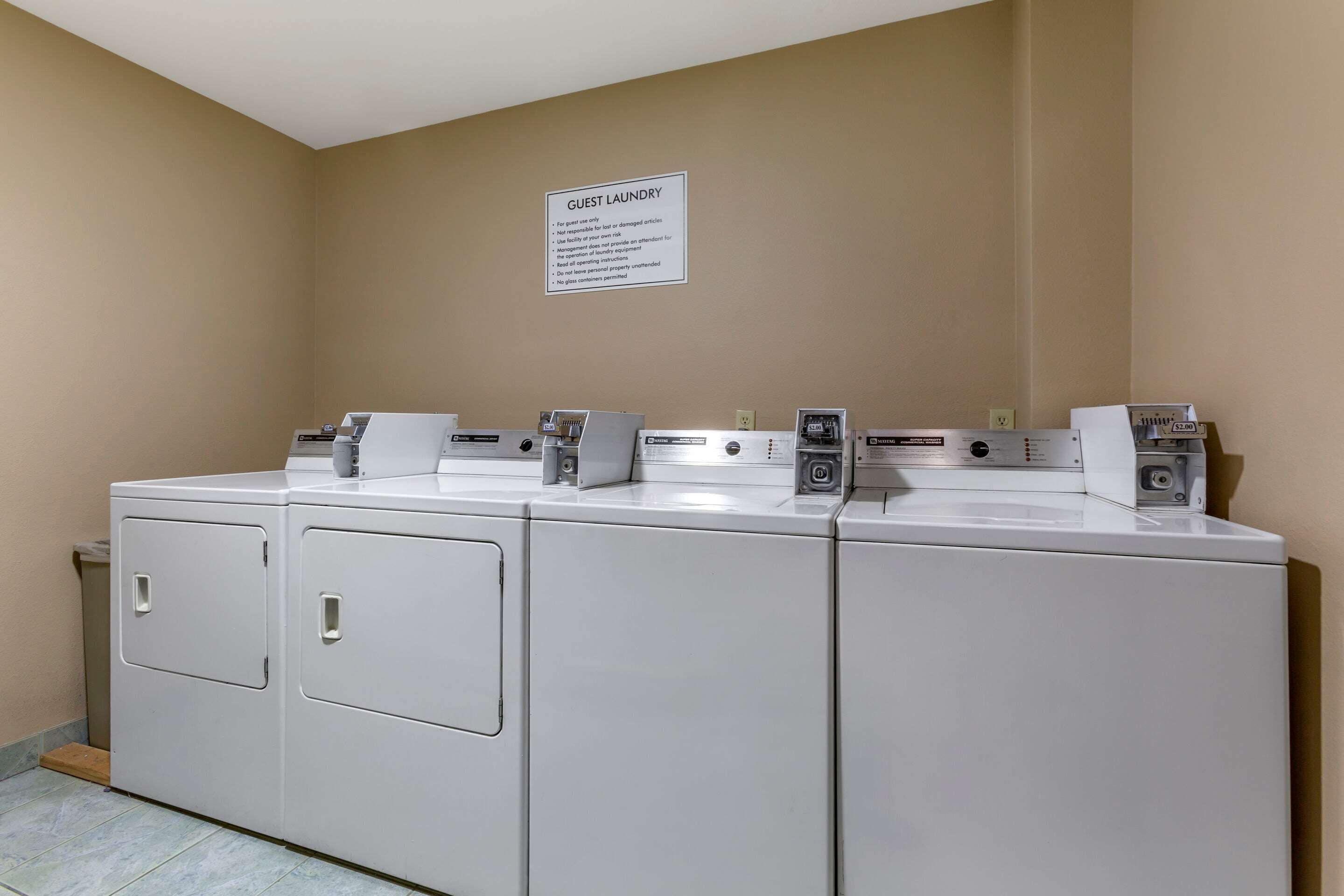 Un espace dédié à la buanderie, avec une pancarte indiquant qu’il est réservé à l’usage des clients, ainsi que des instructions d’utilisation et une note concernant les effets personnels.