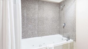 Een moderne badkamer met een vrijstaand bad, een douchekop en een handdoekrek.