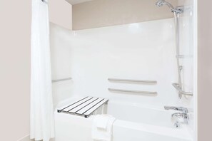Une salle de bain moderne dotée d’une douche à l’italienne, de barres d’appui et d’un porte-serviettes.
