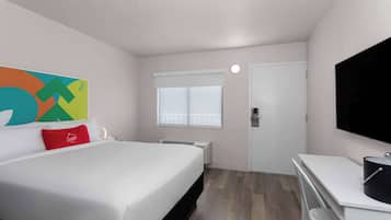 Ein Hotelzimmer mit Bett, Fernseher, Fenster und Bad.