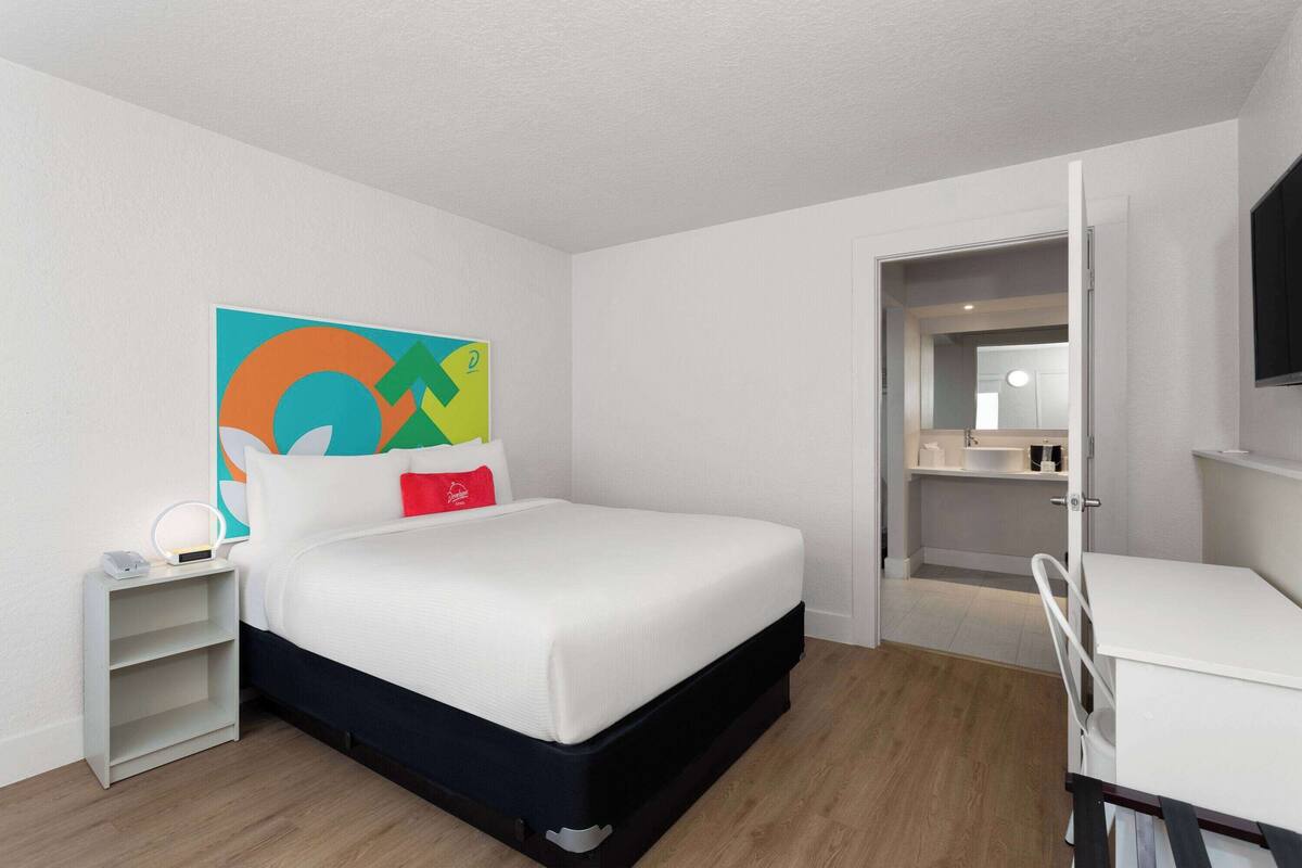 A modern hotel room with a bed, bedside table, and a TV.