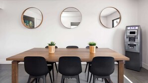 A conference room with a wooden table, black chairs, three round mirrors, and a small ATM machine. - Travelodge by Wyndham Orlando Lake Buena Vista South (Kissimmee)