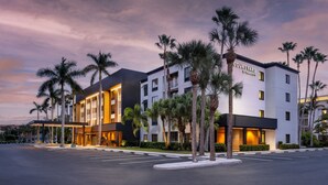 Un hotel Courtyard by Marriott con un diseño moderno, que cuenta con un estacionamiento y palmeras.