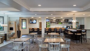 Un restaurante amplio con varias zonas de estar, incluyendo mesas y sillas, y una barra con una vitrina de menú.