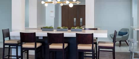 A modern kitchen with a central island, bar stools, and a hanging light fixture.
