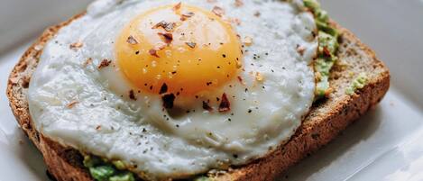A square plate with a toasted bread topped with a fried egg and green spread.