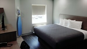 A modern hotel room with a large bed, a desk with a computer, and a window with a view of parked cars. - Hathaway Inn (Panama City)