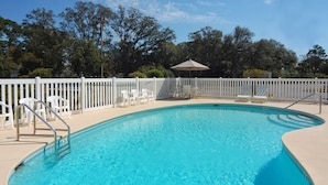 A clear swimming pool with a white fence, lounge chairs, and a shaded area. - Hathaway Inn (Panama City)