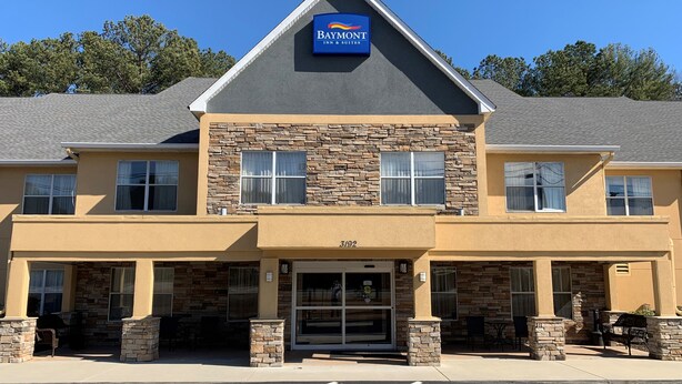 Edificio del Baymont Inn & Suites con fachada de piedra, varias ventanas y cielo despejado.