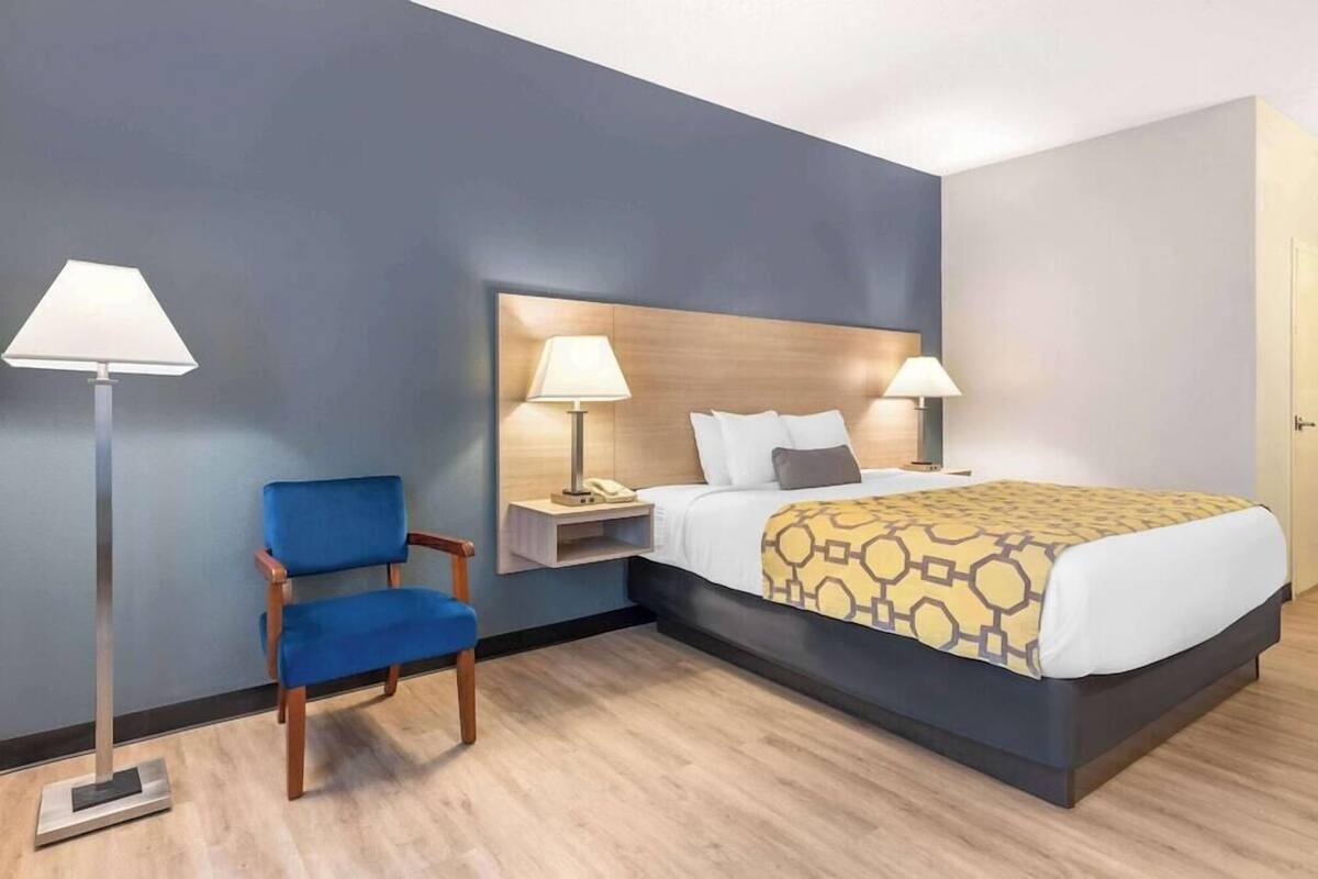 Une chambre d’hôtel avec un lit, des lampes de chevet, une chaise et une table de chevet.