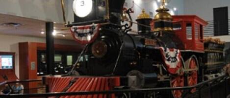 Una locomotora de vapor en exhibición, con un frente rojo, un reloj grande y una cúpula dorada en la parte superior.