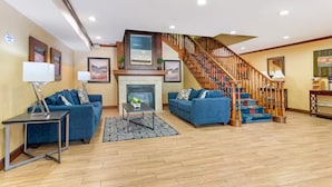 Un salón amplio con chimenea, dos sofás azules, una mesa de centro y una escalera de madera.
