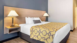Habitación de hotel con una cama grande, dos lámparas de noche, un cabecero de madera y una colcha estampada.