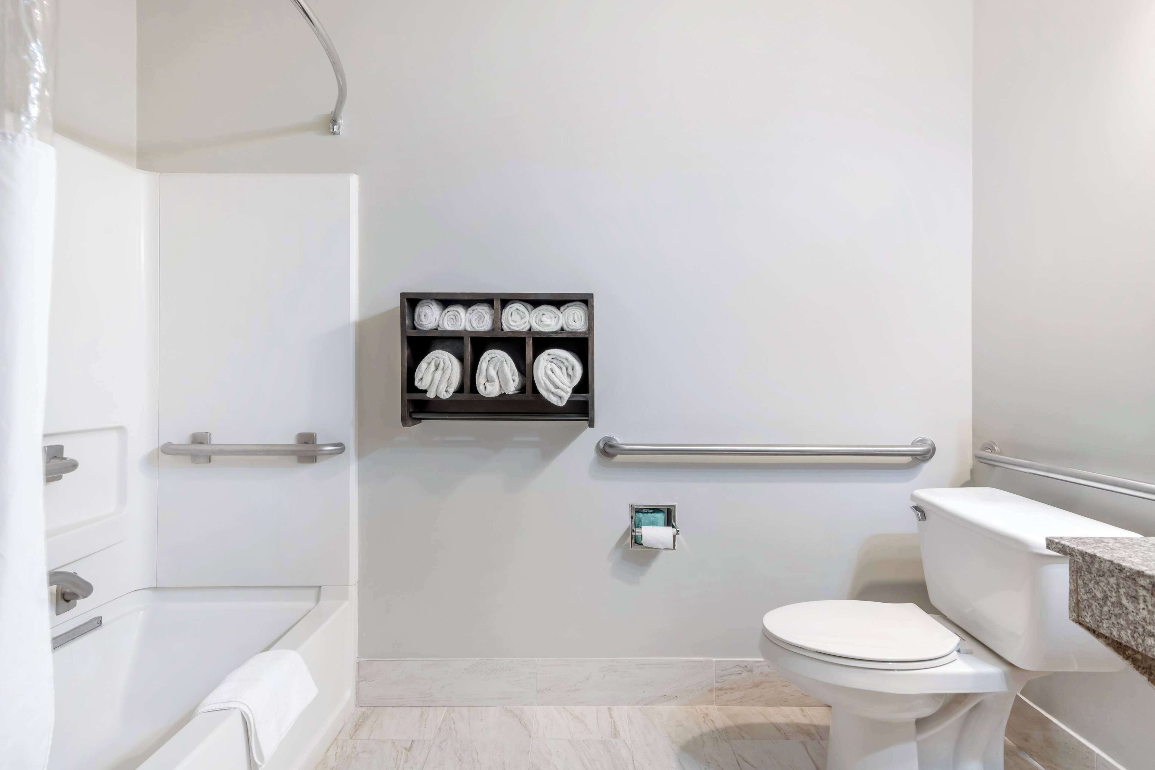 Un baño moderno con bañera, inodoro y un perchero con toallas dobladas con esmero.
