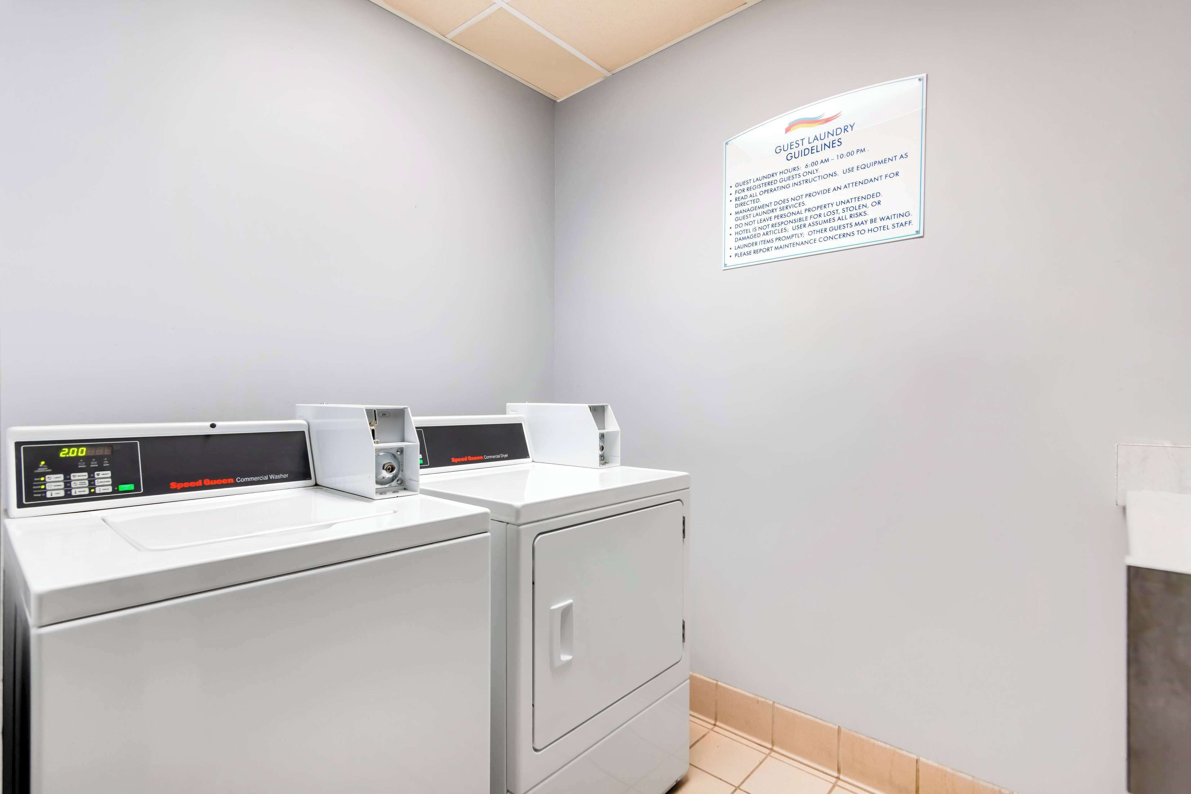 A guest laundry area with two washing machines and a sign detailing guest laundry guidelines.