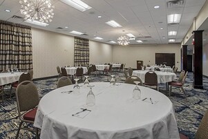 Un salón de conferencias con mesas redondas, sillas y una araña.