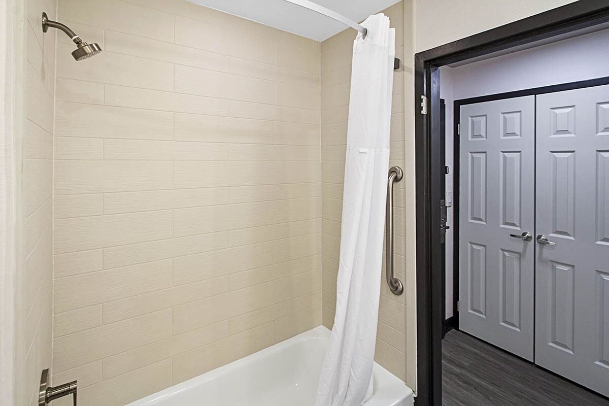 A bathroom with a bathtub, a shower, and a white curtain.