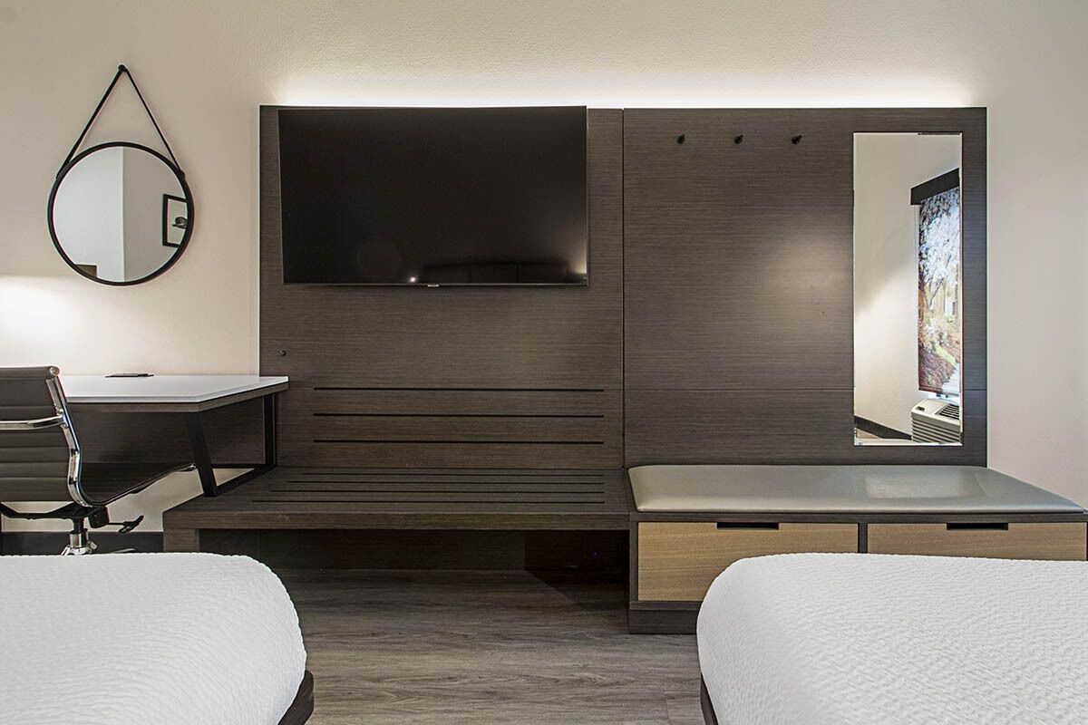 A modern hotel room with a large bed, a desk, and a TV mounted on the wall.