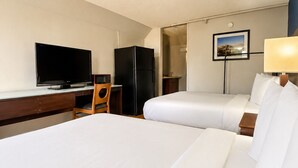 A hotel room with two beds, a television, a refrigerator, a desk, and a lamp. - Heritage Inn Cartersville (Cartersville)