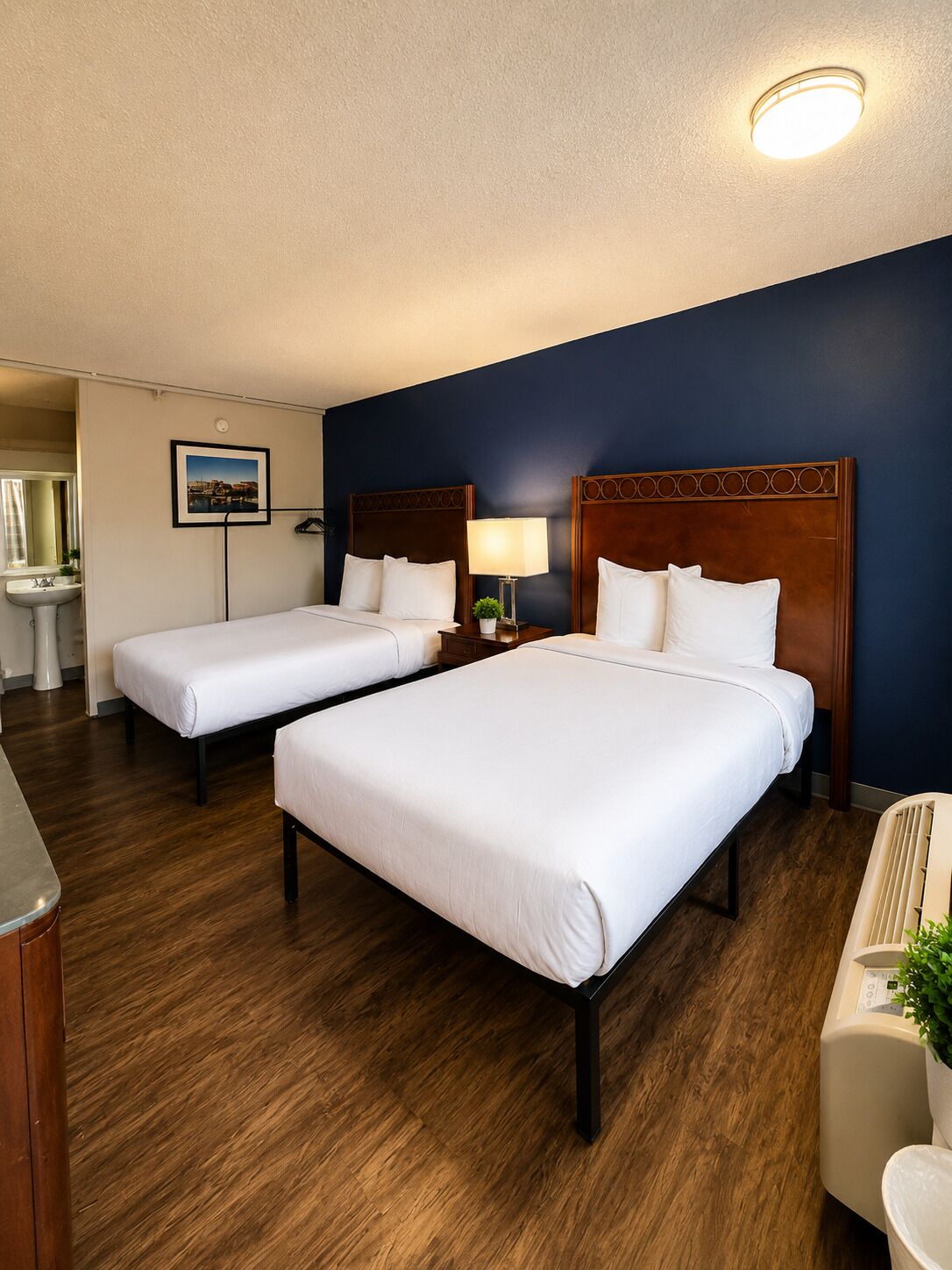 Habitación de hotel con dos camas, baño y vista a la ciudad.