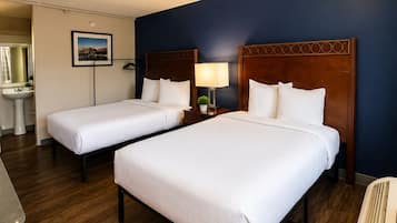 Habitación de hotel con dos camas, baño y vista a la ciudad.