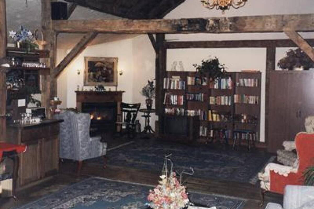 Une pièce rustique avec des poutres apparentes, une cheminée, une bibliothèque et un lustre.