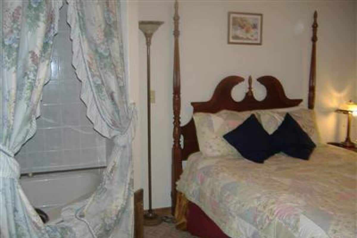 Une chambre à coucher avec un lit à baldaquin, une table de chevet et une fenêtre avec des rideaux.