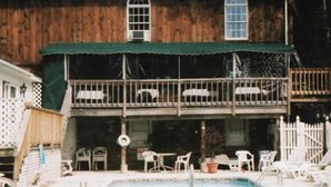 A two-story house with a balcony, a swimming pool, and outdoor furniture. - Sturbridge Country Inn (Fiskdale)