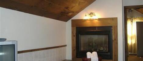 A bathroom with a bathtub, a television, and a fireplace.