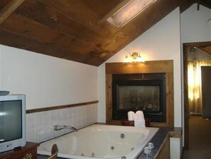 A bathroom with a bathtub, a television, and a fireplace.