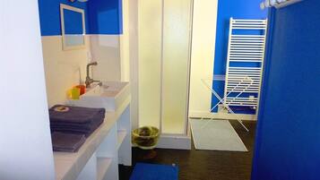 A bathroom with a sink, mirror, towel rack, and a shower area.