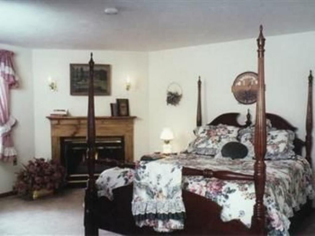 Un dormitorio con cama con dosel, una chimenea y un reloj en la pared.