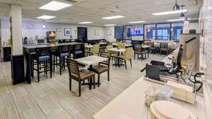 A spacious restaurant with multiple dining areas, a bar, and a pool area visible through the windows.
