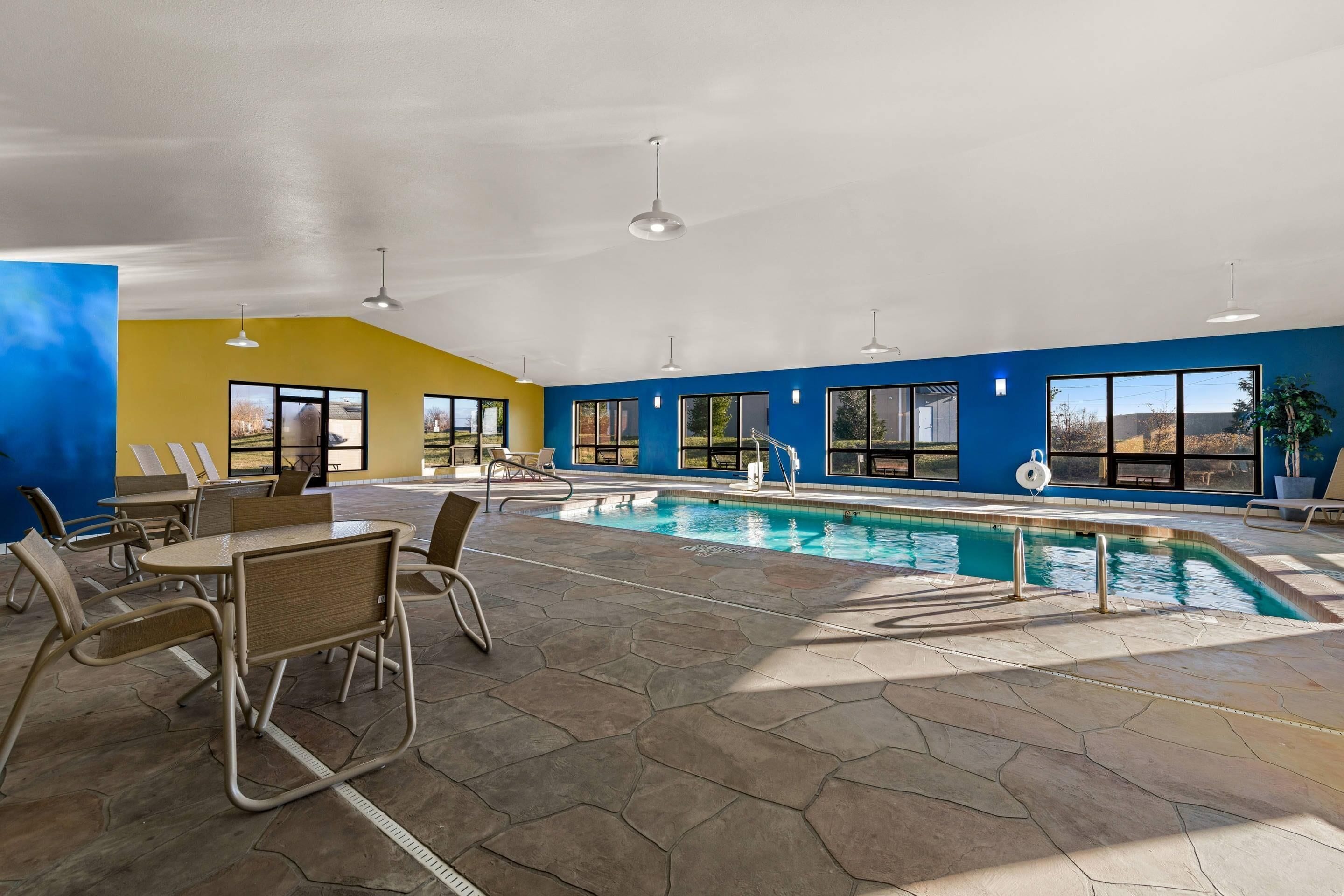 An indoor swimming pool area with hexagonal tiles, seating, and large windows.