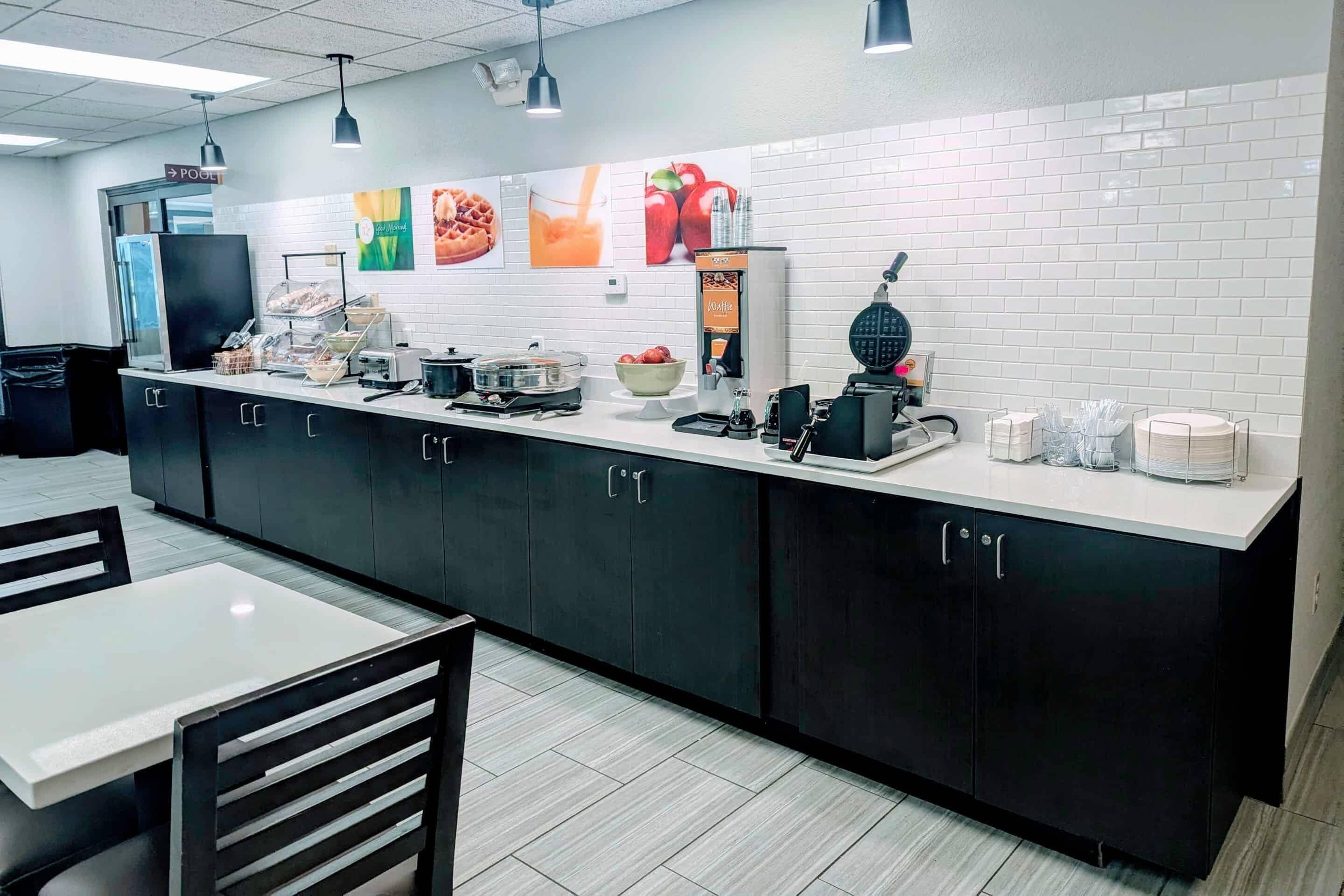 A modern kitchen area with a long counter, various appliances, and a seating area with a table and chairs.