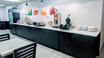 A modern kitchen area with a long counter, various appliances, and a seating area with a table and chairs.