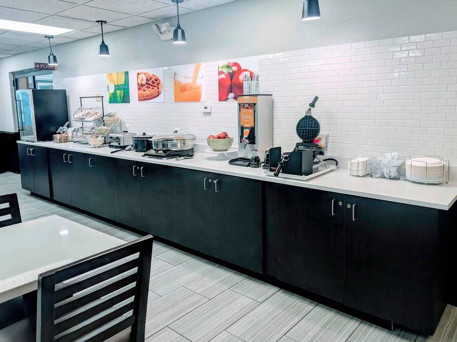 A modern kitchen area with a long counter, various appliances, and a seating area with a table and chairs.