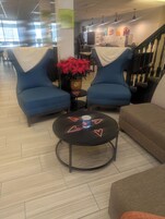 Una zona de estar con dos sillones azules, una mesa redonda con palomitas y adornos con forma de corazón, y una planta en maceta.