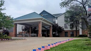 A Quality Inn with a covered entrance, brick buildings, and American flags lining the driveway.