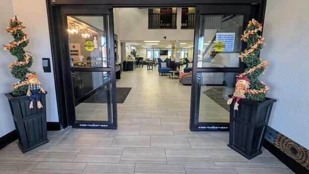 A hotel lobby with a modern interior, featuring a reception desk, seating areas, and a staircase.