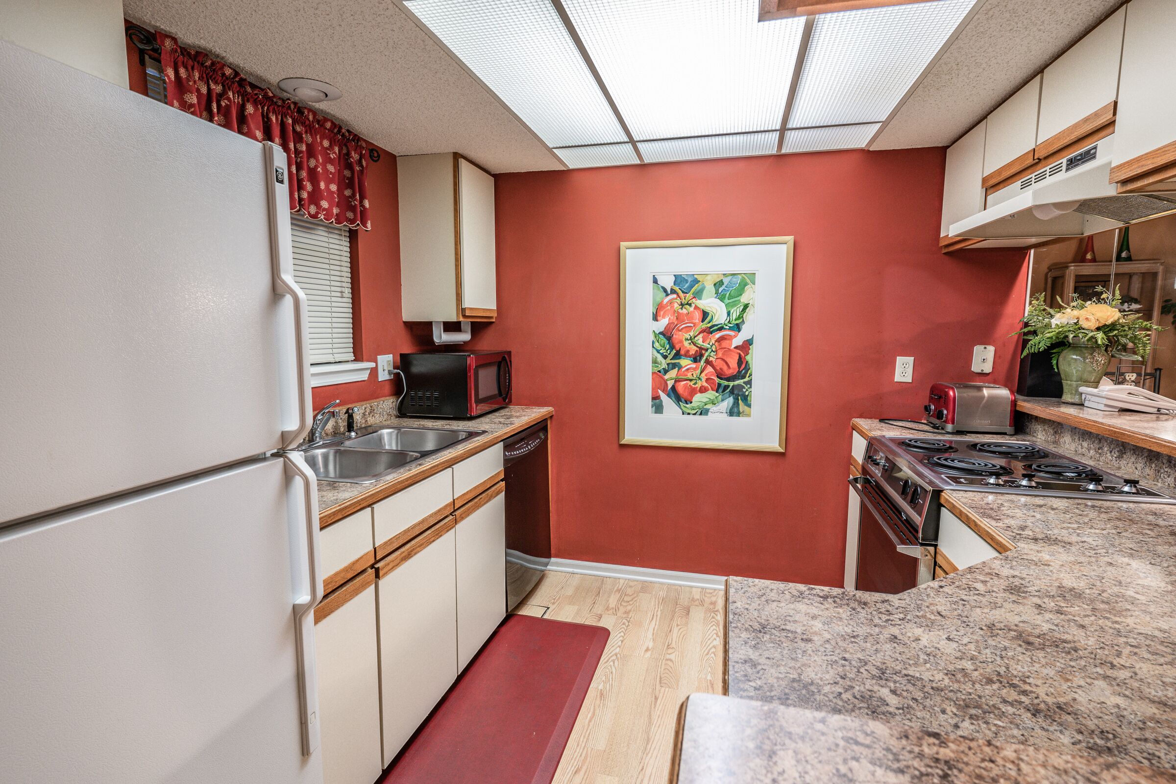 A compact kitchen with a refrigerator, microwave, sink, and stove.