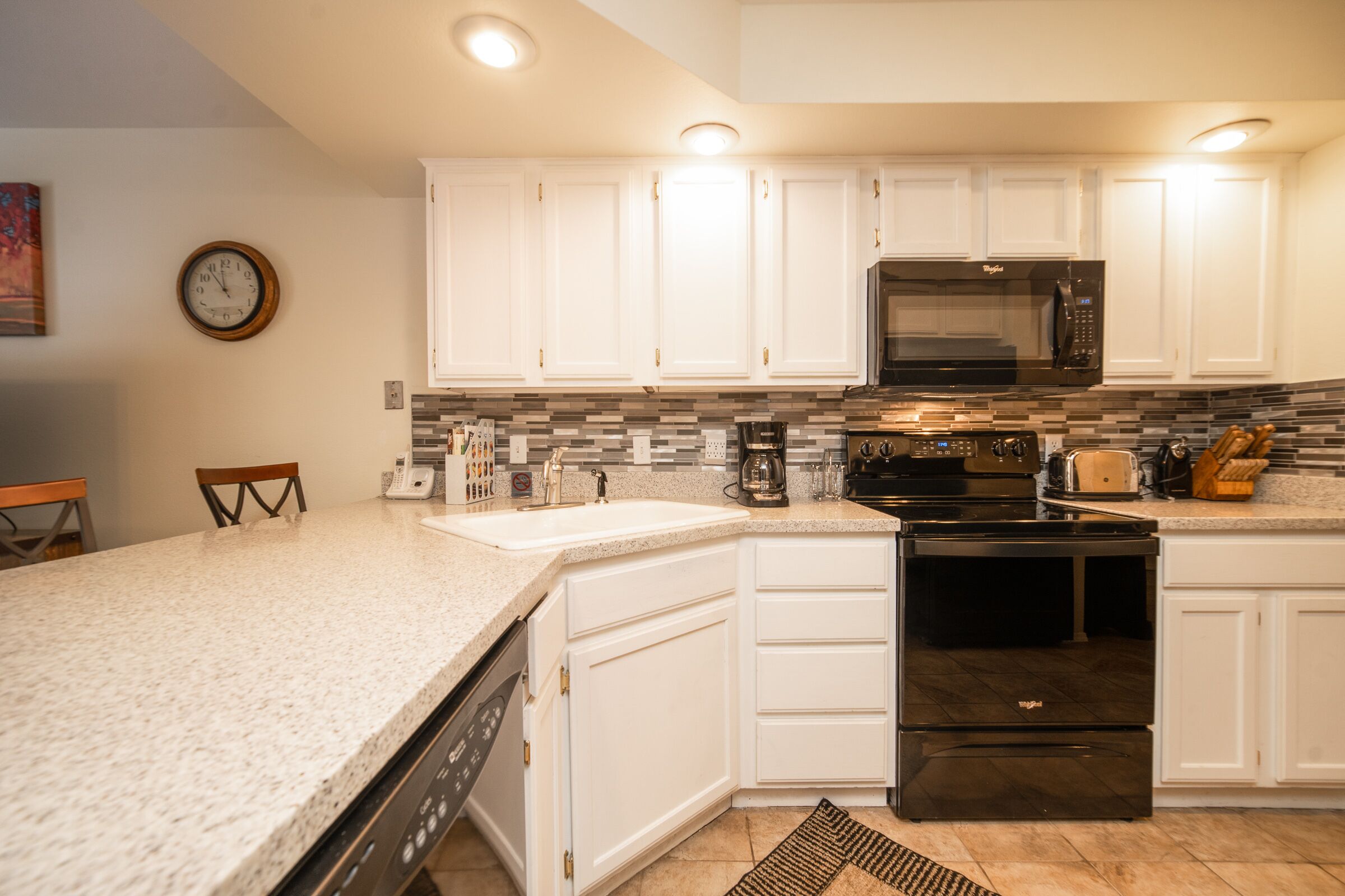 A modern kitchen with white cabinets, a black microwave, and a stainless steel stove.