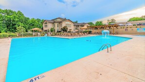 A swimming pool with a 4 FT depth marker, surrounded by a fence, with a building in the background. - Pointe Royale Condominium Resort & Golf Course (Branson)