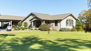 A stone building with a covered entrance and a flag on the lawn. - Pointe Royale Condominium Resort & Golf Course (Branson)