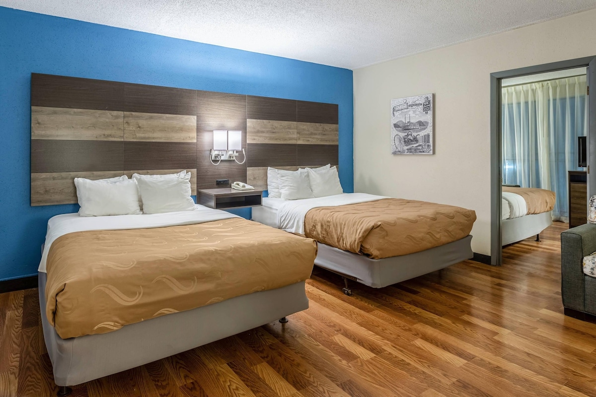 A hotel room with two beds, a nightstand, a phone, and a painting on the wall.