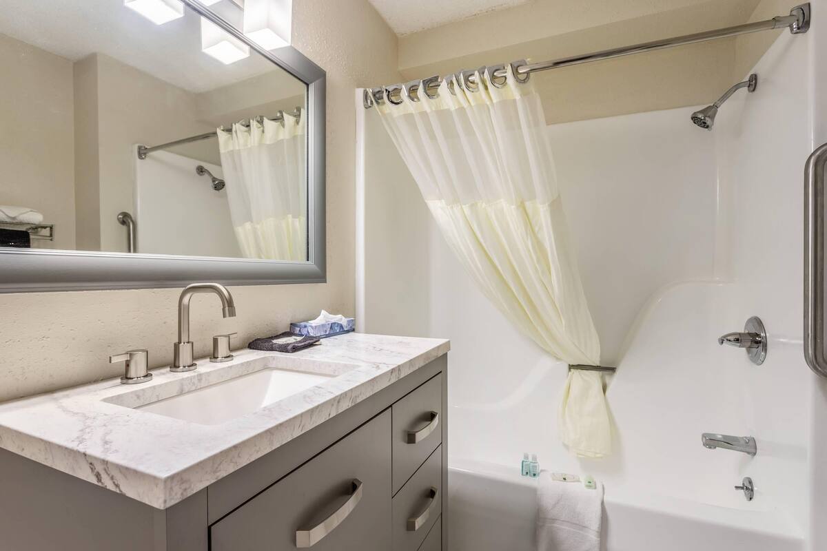 A bathroom with a sink, mirror, shower, and bathtub.