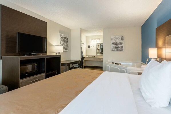 Une chambre d’hôtel équipée d’un lit, d’une télévision, d’un four à micro-ondes, d’un bureau et d’une salle de bain.